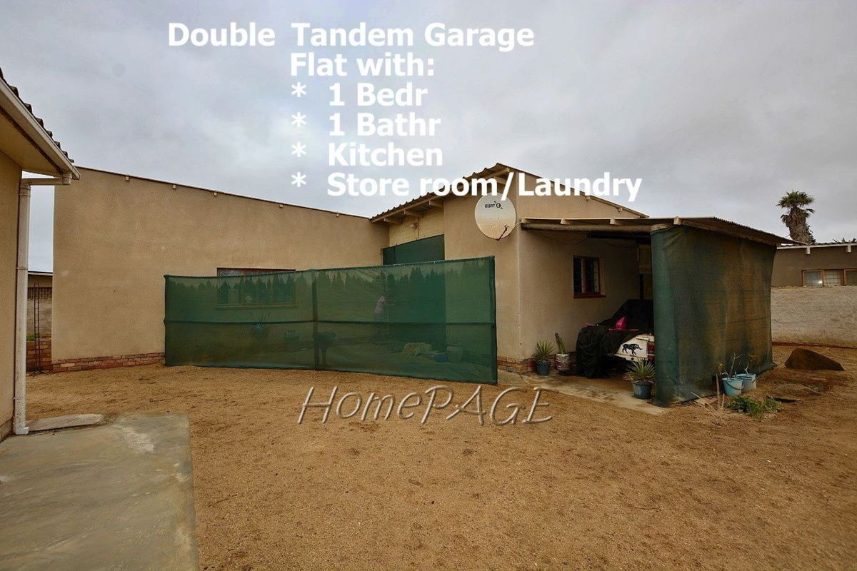 Rear exterior view of the property featuring a garage structure with an attached flatlet, including a bedroom, bathroom, kitchen, and laundry area.