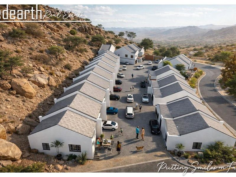 Aerial view of a modern townhouse complex development nestled against a rocky hillside, featuring paved driveways and uniform architectural design.