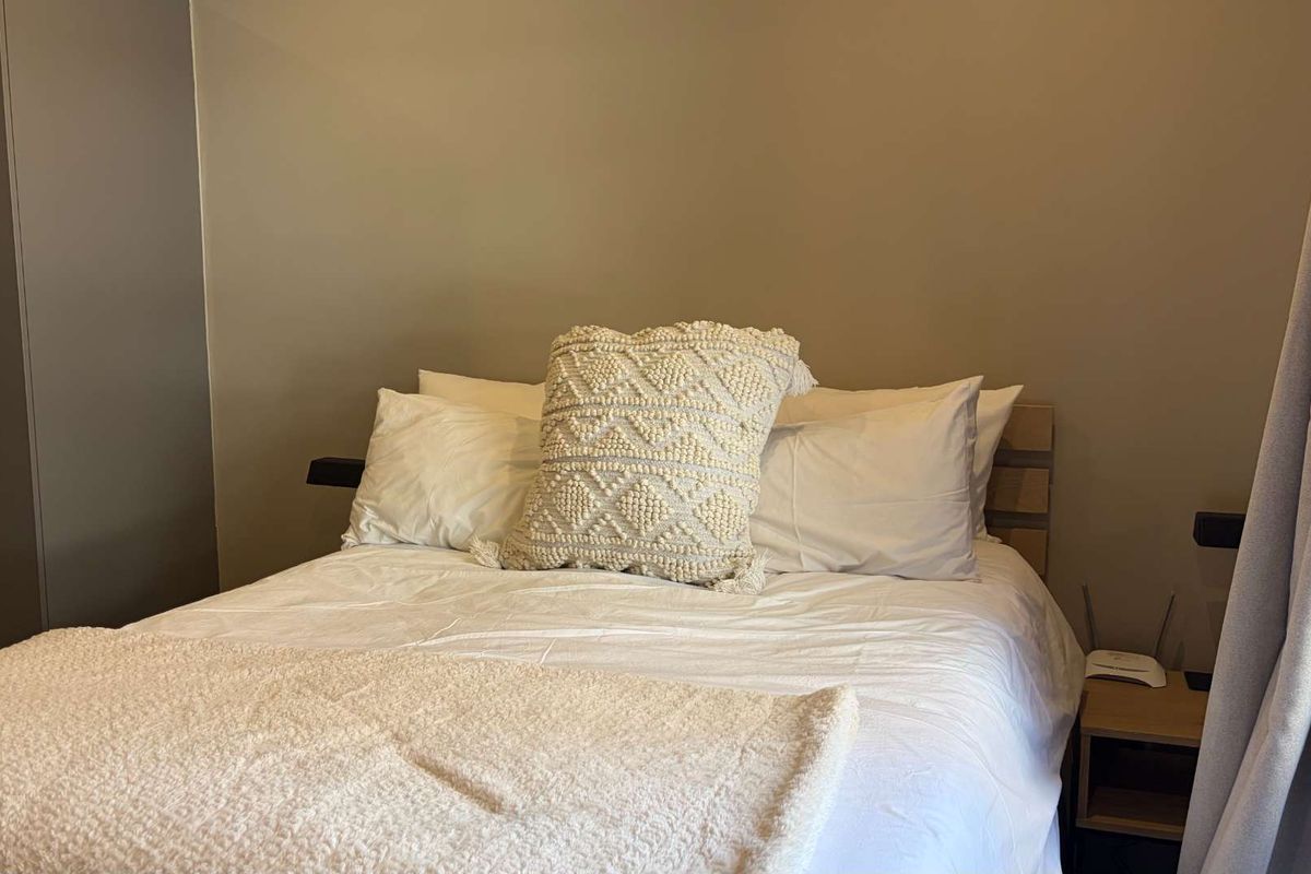 A well-maintained bedroom featuring neutral wall tones and a built-in cupboard for storage.