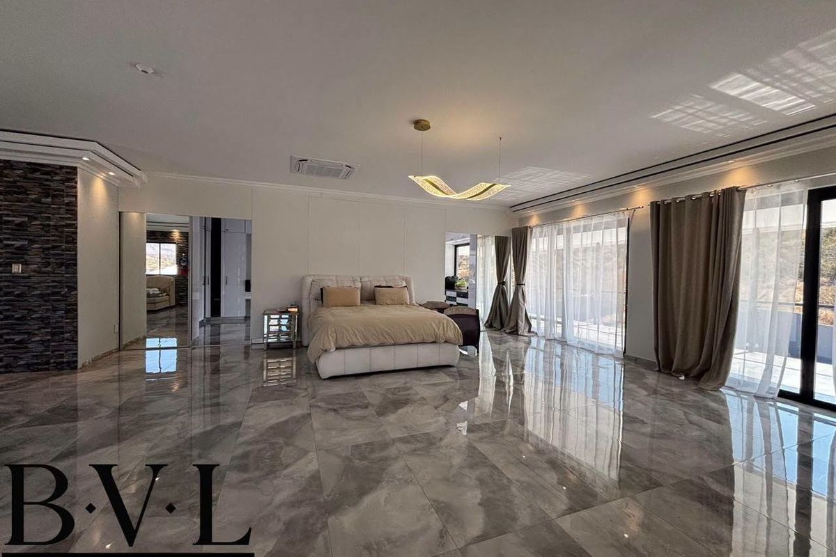 Spacious master bedroom featuring large format polished floor tiles, a stone feature wall, ducted air conditioning, and direct access to an outdoor area.