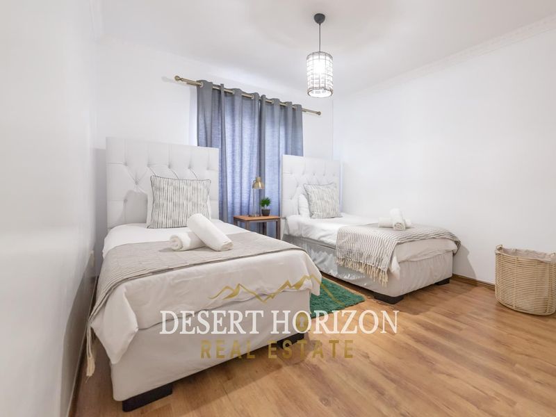 A well-maintained bedroom featuring laminate flooring, neutral walls, and a modern pendant light fixture.