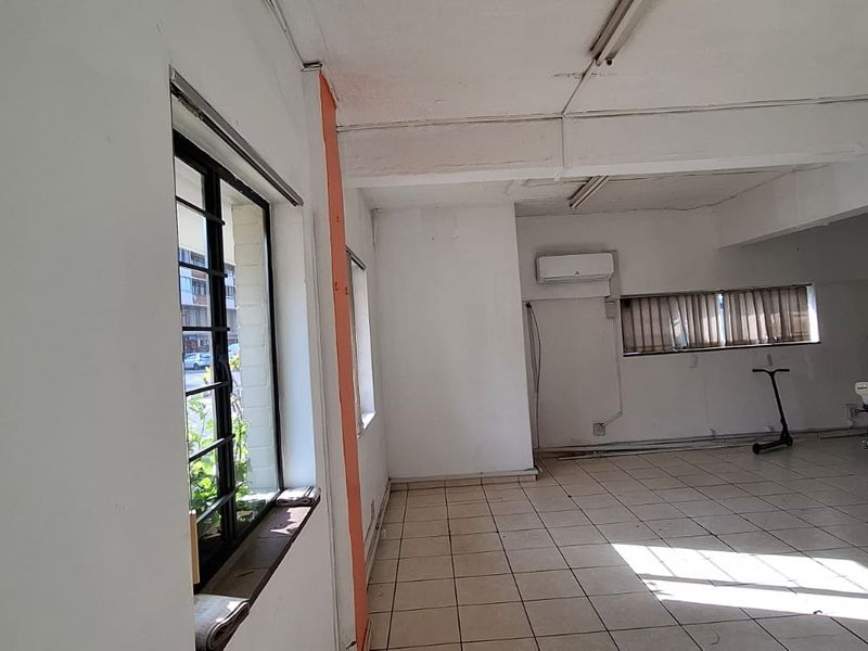 Open-plan office space featuring tiled flooring, split-system air conditioning, and large windows with security bars, offering a functional layout for business operations.