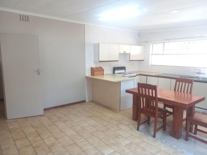 Open-plan kitchen and dining area featuring tiled flooring, built-in cabinetry, and a functional electric stove, offering a practical layout for daily living.