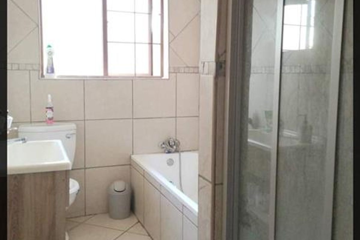 A functional bathroom featuring a built-in bathtub, a separate shower enclosure, and a vanity unit with a basin.