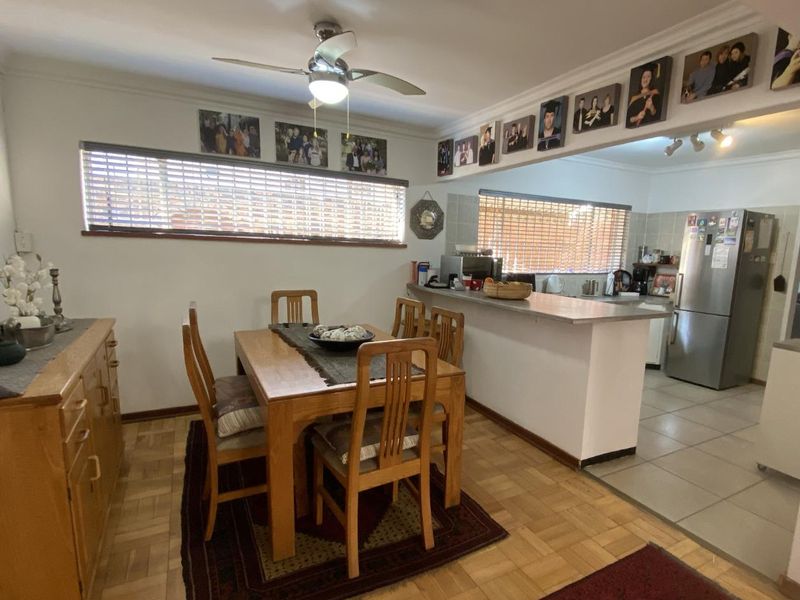 Open plan dining area and kitchen featuring a breakfast bar, parquet flooring, and a ceiling fan, creating a functional and connected living space.