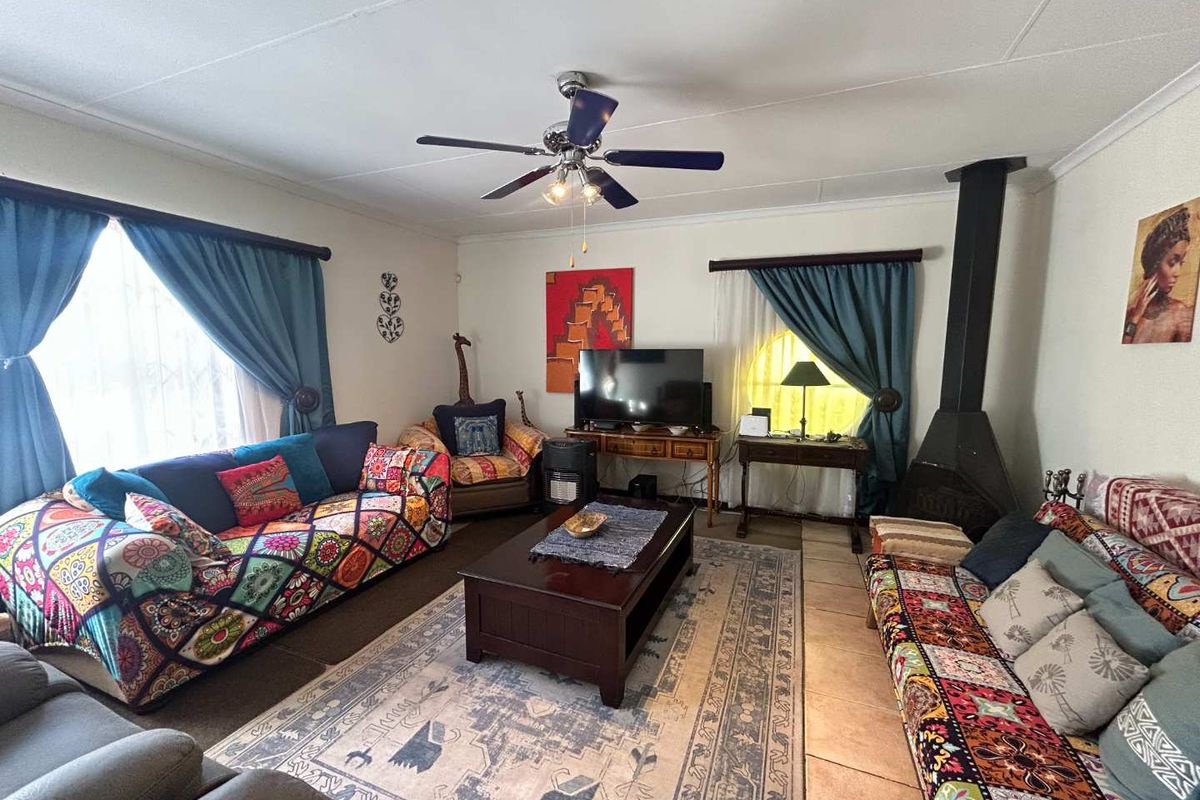 A spacious living room featuring a central ceiling fan, tiled flooring, and a prominent freestanding fireplace, offering a comfortable and functional living space.