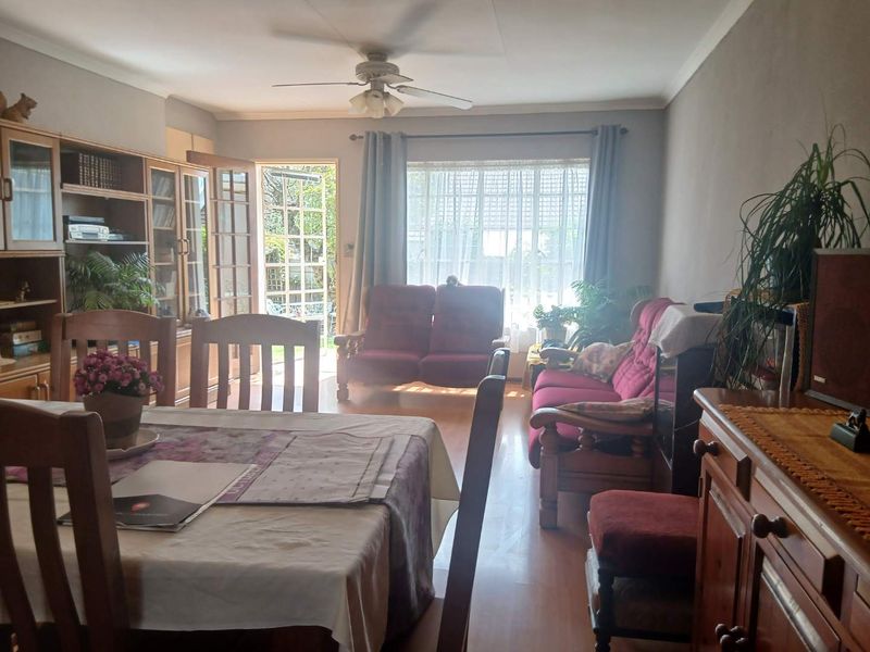 Open plan living and dining area featuring laminate flooring, a ceiling fan, and direct access to the garden through a glass panelled french door.