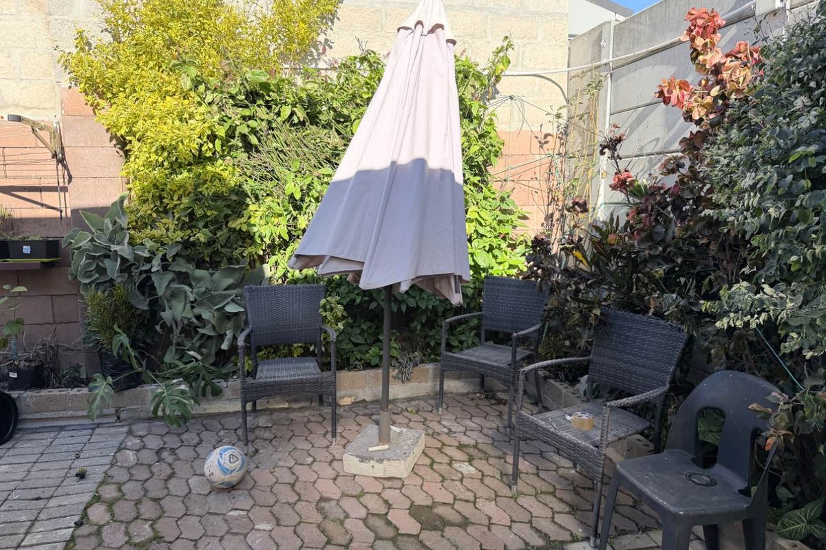 A small rear courtyard area featuring paved flooring and boundary walls, currently used as an outdoor seating space.