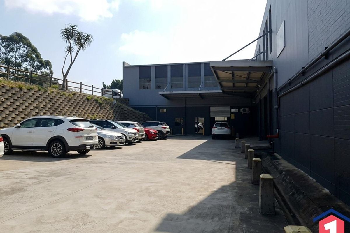 Industrial rear yard featuring a concrete surface, retaining wall, loading canopy, and roller shutter access point.