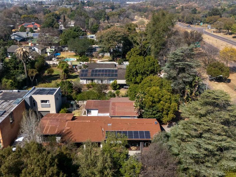 Aerial view of the property showcasing the roof structure, installed solar panels, and surrounding residential neighbourhood and garden area.