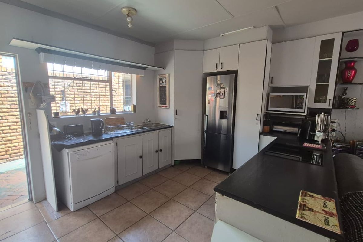Functional kitchen featuring tiled flooring, ample built-in cabinetry, laminate countertops, and direct access to an outdoor area.