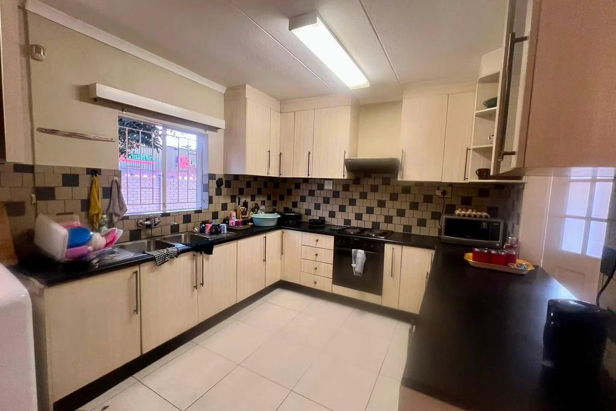 Functional kitchen featuring light-toned cabinetry, dark countertops, tiled backsplash, and integrated appliances, offering a practical layout for daily cooking and preparation.