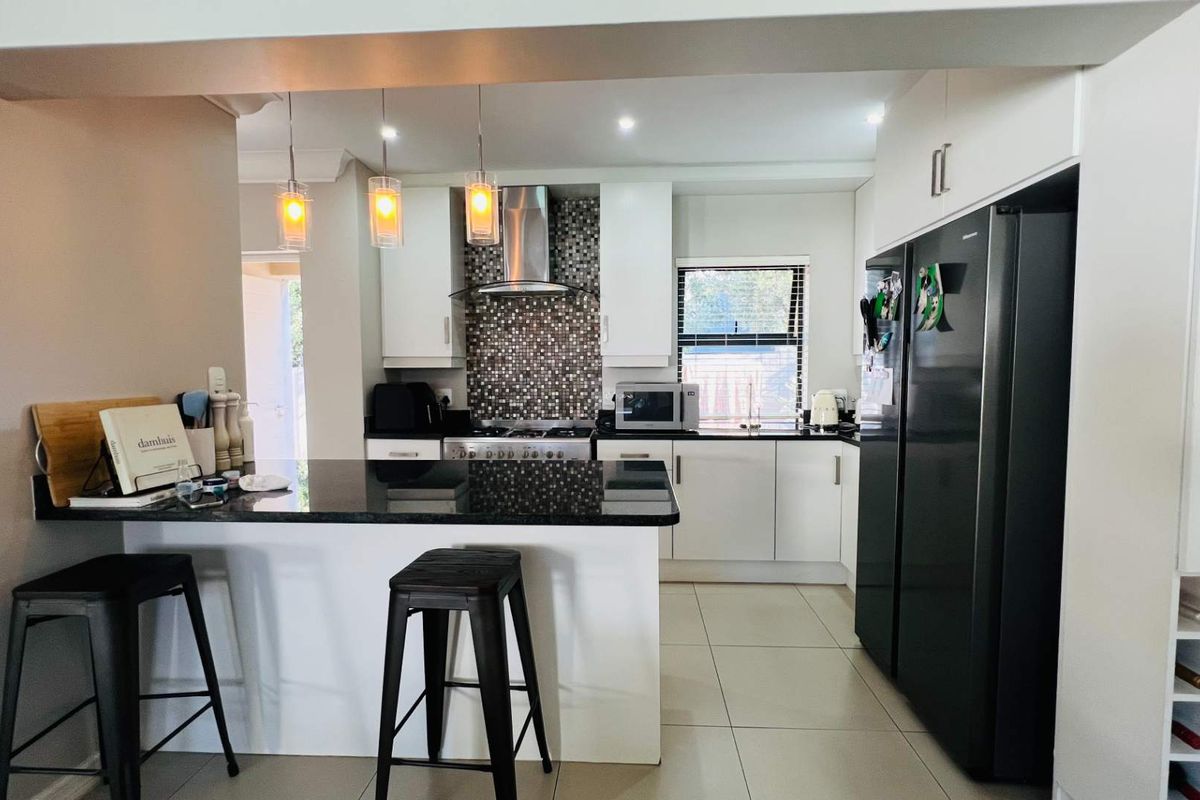 Modern kitchen featuring granite countertops, a mosaic tile backsplash, stainless steel extractor fan, gas hob, and ample built-in cabinetry with recessed lighting.