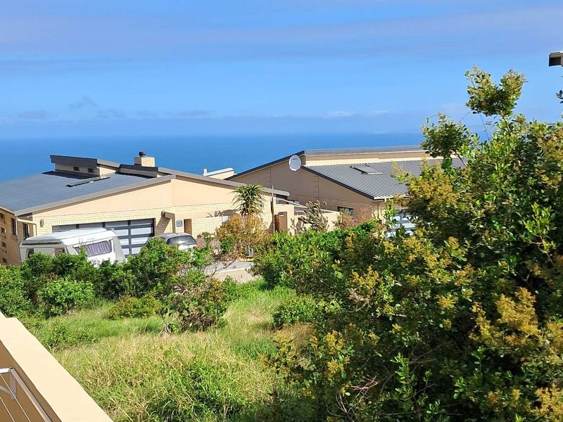 A scenic elevated view overlooking neighboring residential properties with a clear horizon line of the ocean.