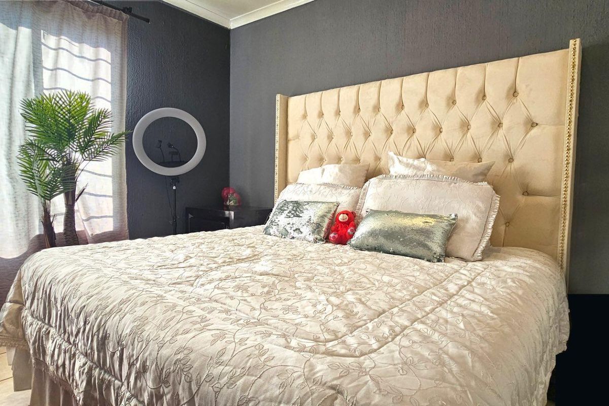 A bedroom featuring dark textured walls, tiled flooring, and a large window with curtains.