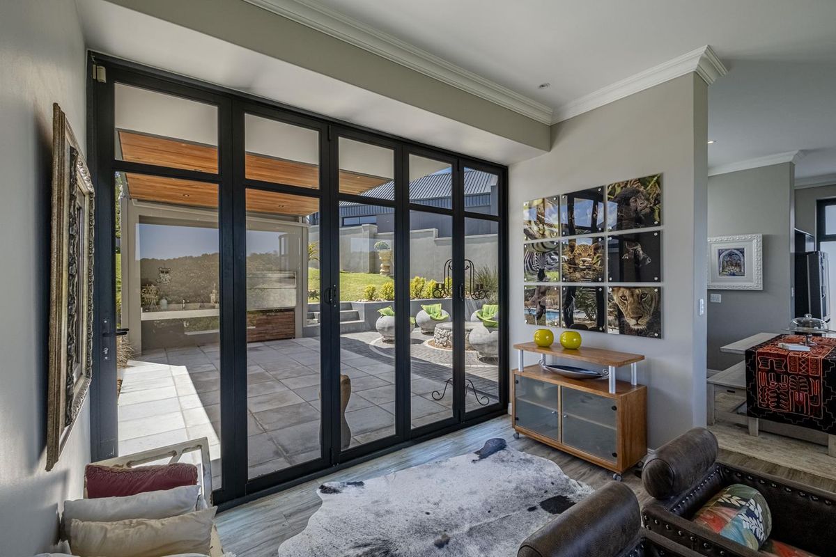 A bright living area featuring large black-framed glass stacker doors that provide seamless access to an outdoor patio and garden space.