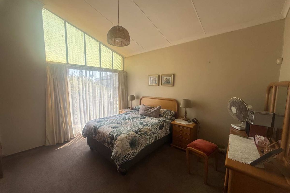 A spacious bedroom featuring a high raked ceiling and a large window that allows for ample natural light.