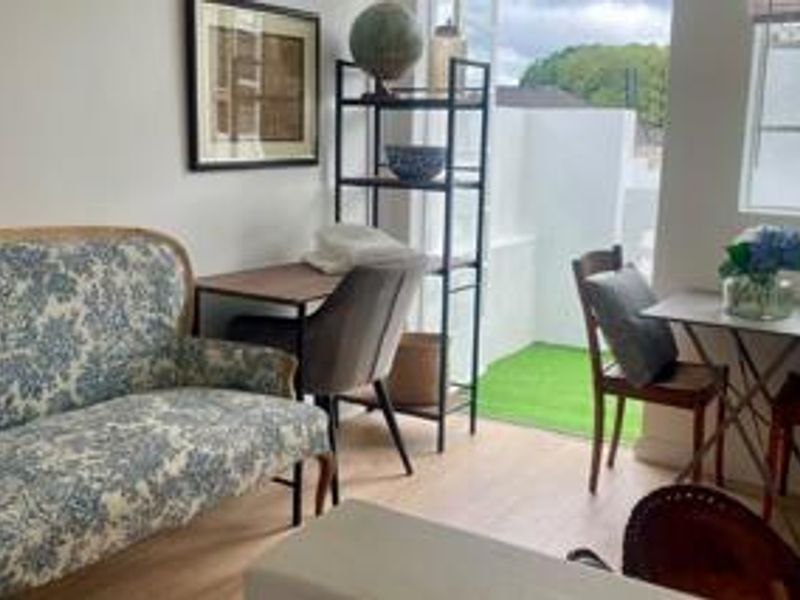 A bright living area featuring laminate flooring and a sliding glass door providing direct access to a small outdoor patio space.