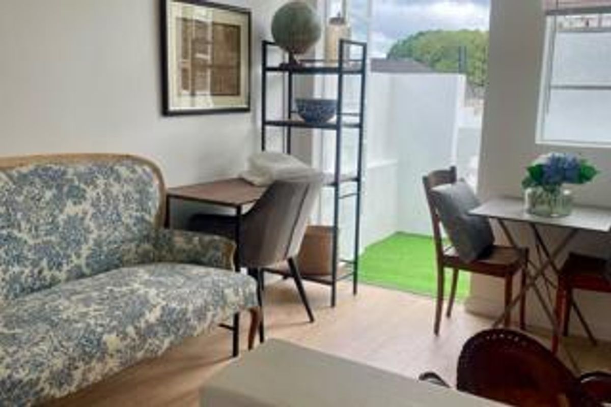 A bright living area featuring laminate flooring and a sliding glass door providing direct access to a small outdoor patio space.