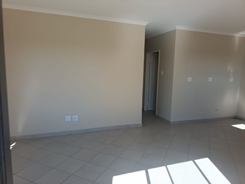 A bright, empty living area featuring neutral wall tones, tiled flooring, and coved cornicing, providing a clean and versatile space for interior design.