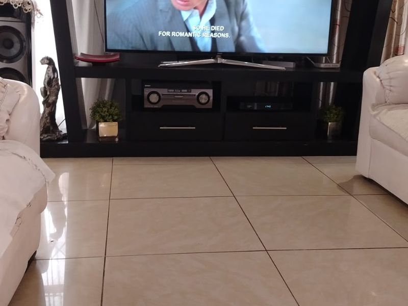 A living room area featuring large format polished porcelain floor tiles and a built-in media entertainment unit.