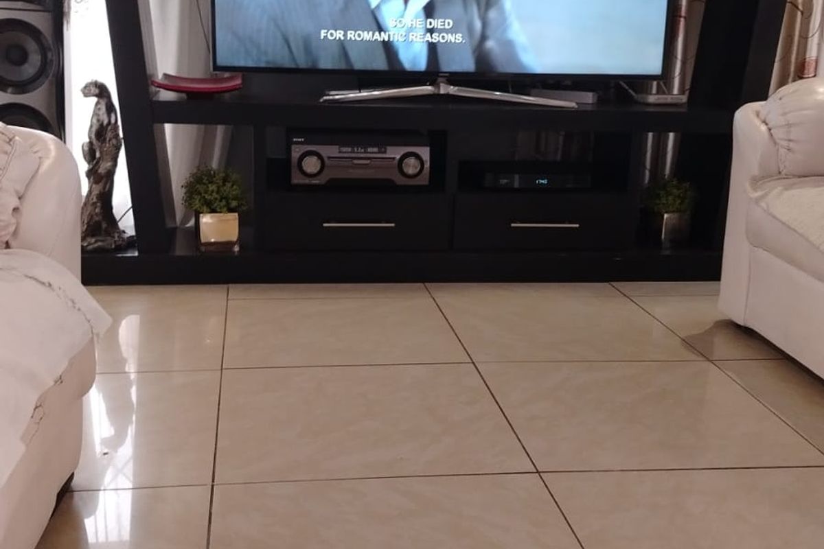 A living room area featuring large format polished porcelain floor tiles and a built-in media entertainment unit.