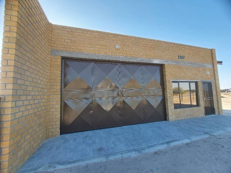 Front exterior view of an industrial property featuring a large metal garage door, brick facade, and paved driveway entrance.