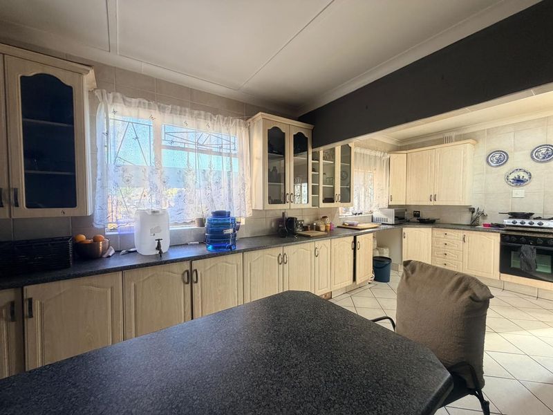 A functional kitchen featuring light-toned built-in cabinetry, dark laminate countertops, tiled backsplash, and a built-in oven with hob.