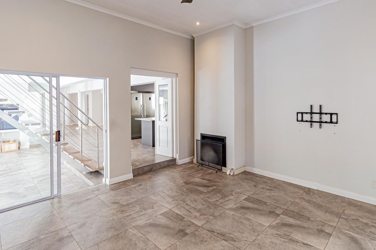 Spacious living area featuring large format floor tiles, a built-in fireplace, and direct access to an adjacent staircase and kitchen area.