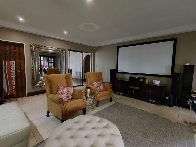 A dedicated cinema room featuring a large built-in projection screen, tiled flooring, and recessed downlighting, providing a comfortable space for home entertainment.