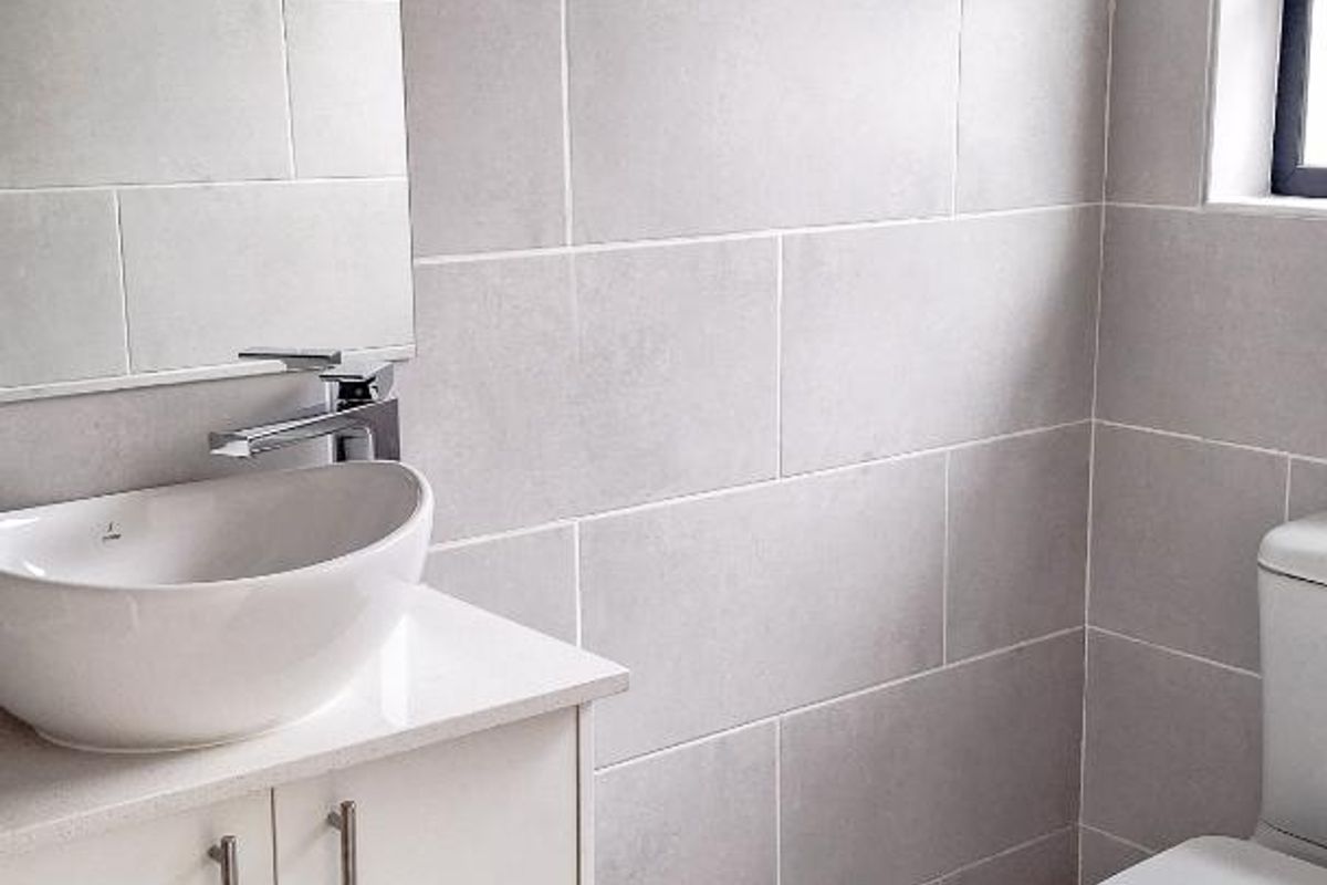 Modern bathroom featuring a sleek vanity with a vessel sink, contemporary chrome faucet, and neutral wall tiling.