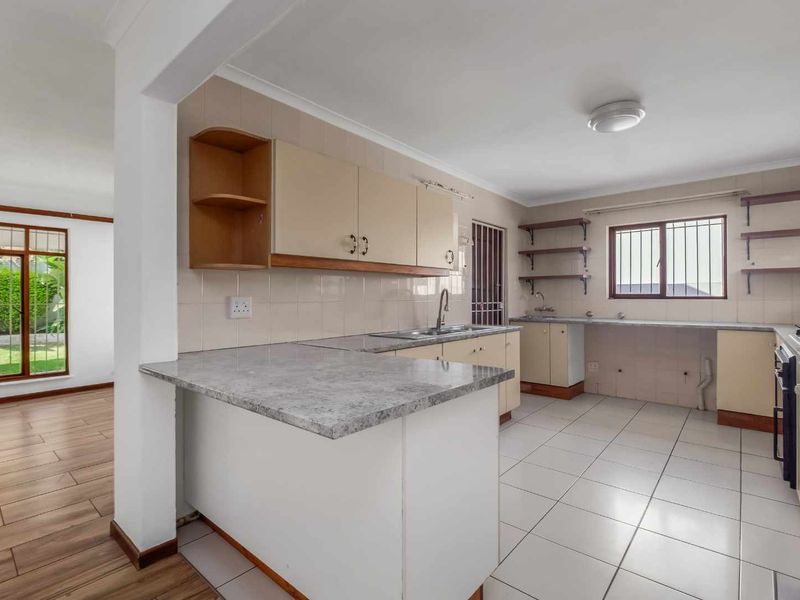 A functional, empty kitchen featuring built-in cabinetry, laminate countertops, a built-in oven, and tiled flooring, offering a clean canvas for potential updates.