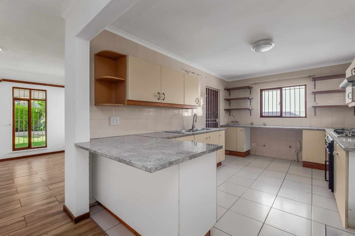A functional, empty kitchen featuring built-in cabinetry, laminate countertops, a built-in oven, and tiled flooring, offering a clean canvas for potential updates.