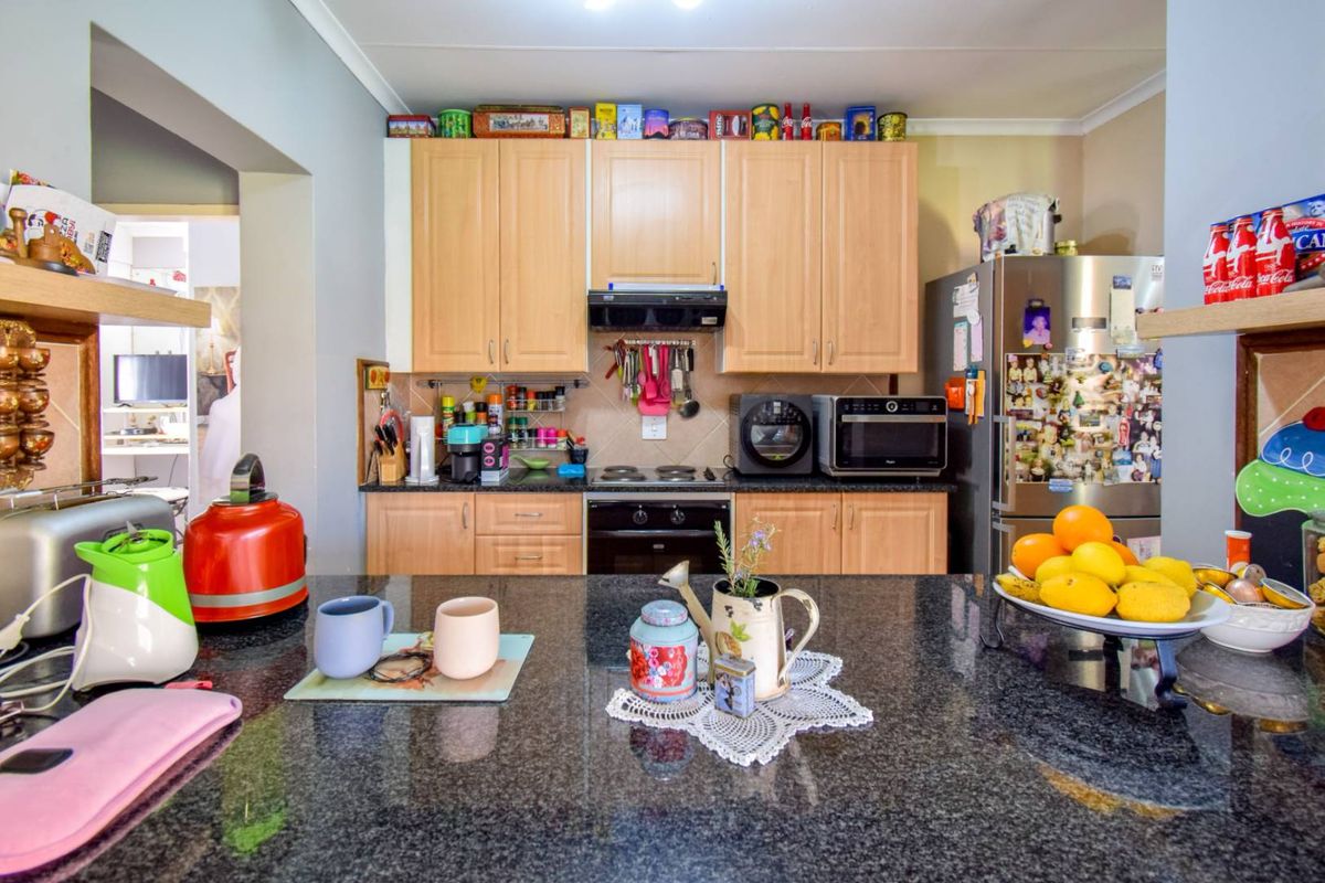 A functional kitchen featuring granite countertops, light wood cabinetry, and integrated appliances including an oven, hob, and extractor fan.