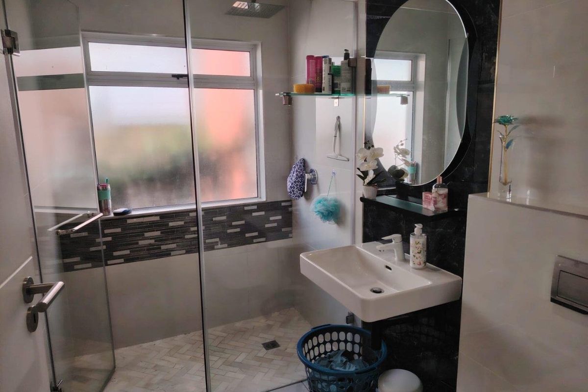 Modern bathroom featuring a walk-in shower with glass screen, wall-mounted basin, and contemporary tiled finishes.