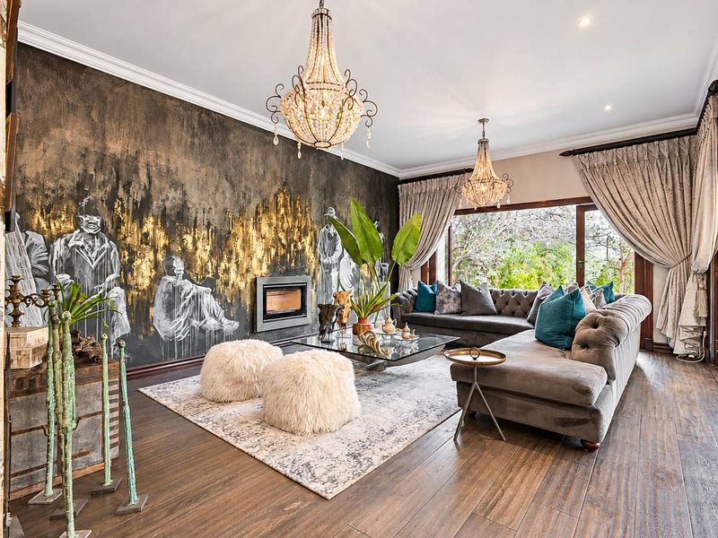 Elegant living room featuring hardwood flooring, a built-in fireplace with artistic wall treatment, crystal chandeliers, and large sliding doors opening to the garden.