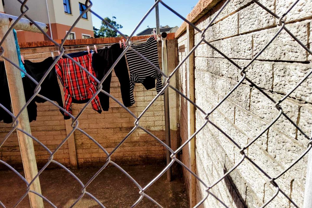 A utilitarian outdoor drying area enclosed by a chain-link fence and masonry boundary walls.