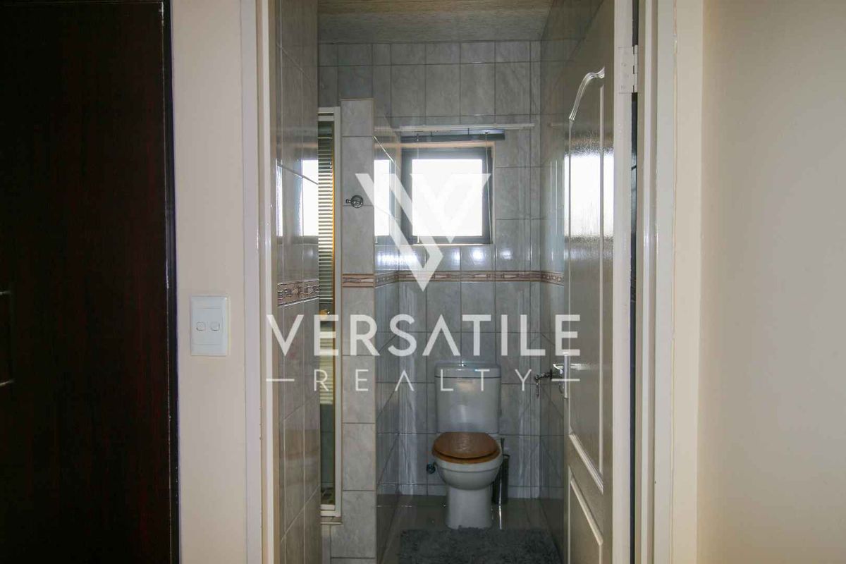 A compact bathroom featuring tiled walls, a shower enclosure, and a standard toilet, viewed through a doorway.
