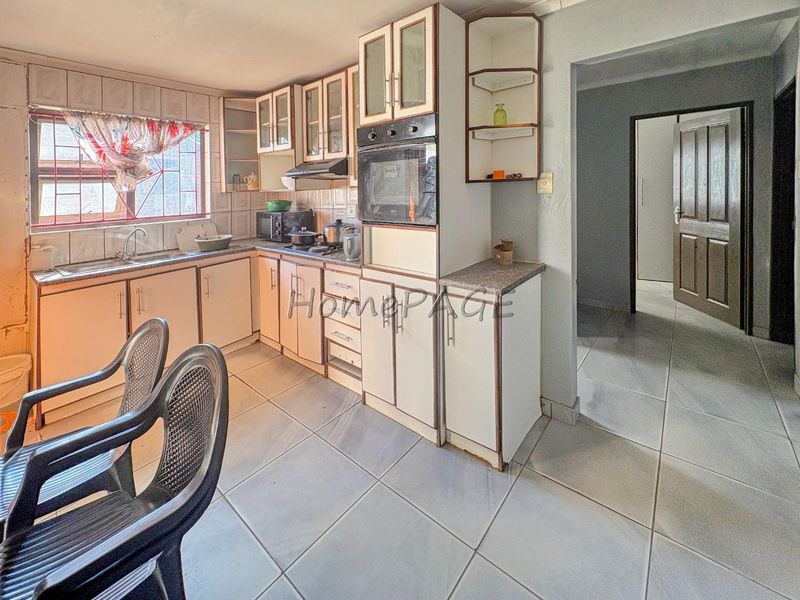 A dated kitchen featuring built-in cabinetry, laminate countertops, a built-in oven, and tiled flooring, offering potential for a modern renovation.