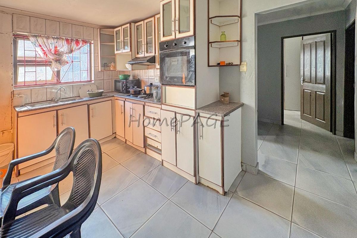 A dated kitchen featuring built-in cabinetry, laminate countertops, a built-in oven, and tiled flooring, offering potential for a modern renovation.