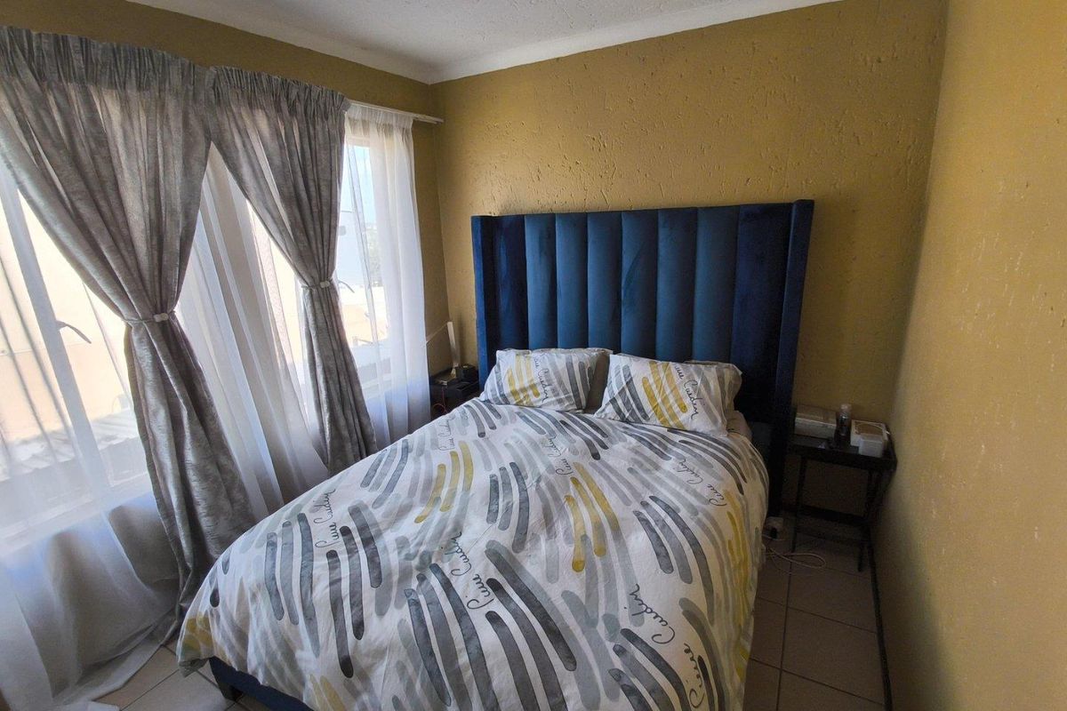 A bedroom featuring tiled flooring and a large window with curtain tracks, providing natural light to the space.