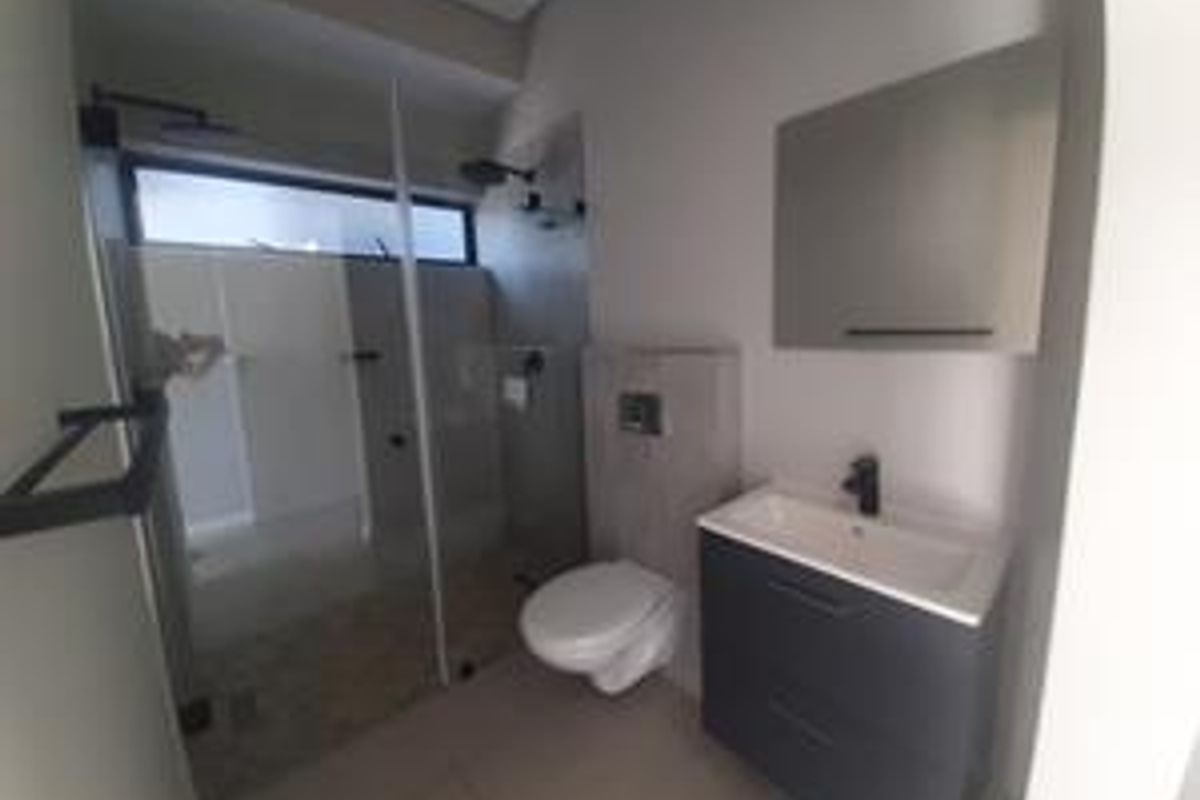 Modern bathroom featuring a walk-in shower with glass screen, wall-mounted toilet, and a sleek vanity cabinet with basin.