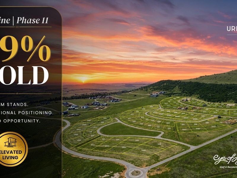 Aerial view of a residential estate development featuring marked land plots and paved road infrastructure at sunset.