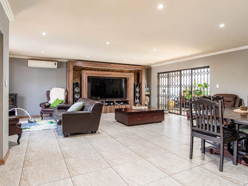 Spacious open-plan living and dining area featuring tiled floors, recessed lighting, a built-in media unit, and direct access to the patio through sliding doors.