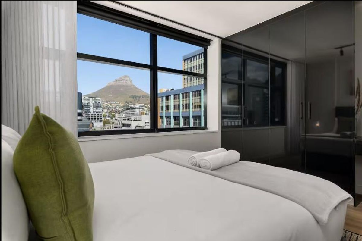 Modern bedroom featuring floor-to-ceiling built-in cupboards and large windows offering expansive city and mountain views.