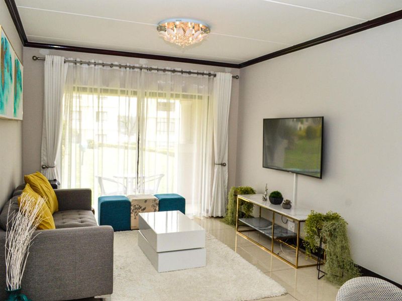 A well-maintained living room featuring tiled flooring, a decorative ceiling light, and a large sliding glass door providing access to the patio.