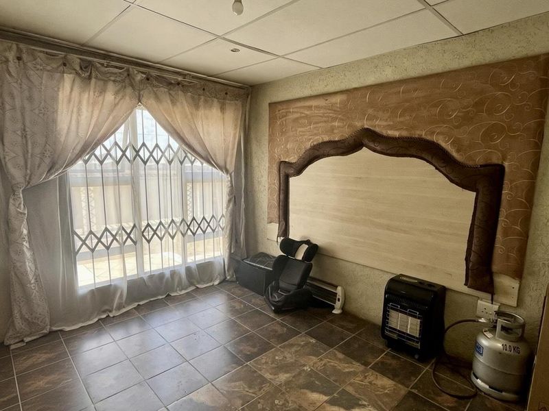 A bedroom featuring tiled flooring, a drop ceiling, and a decorative wall panel, with a sliding door leading to an outdoor area.