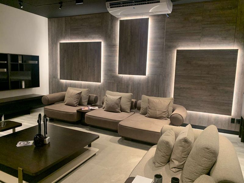 Modern living area featuring sophisticated wood-look wall paneling with integrated LED accent lighting and a wall-mounted air conditioning unit.