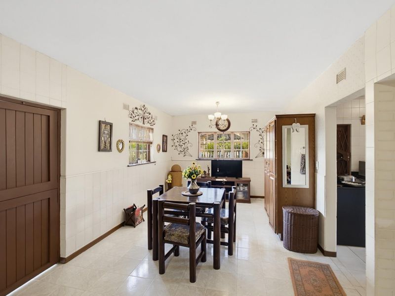 Open plan living and dining area featuring tiled flooring and wall cladding, providing a functional space with direct access to the kitchen area.