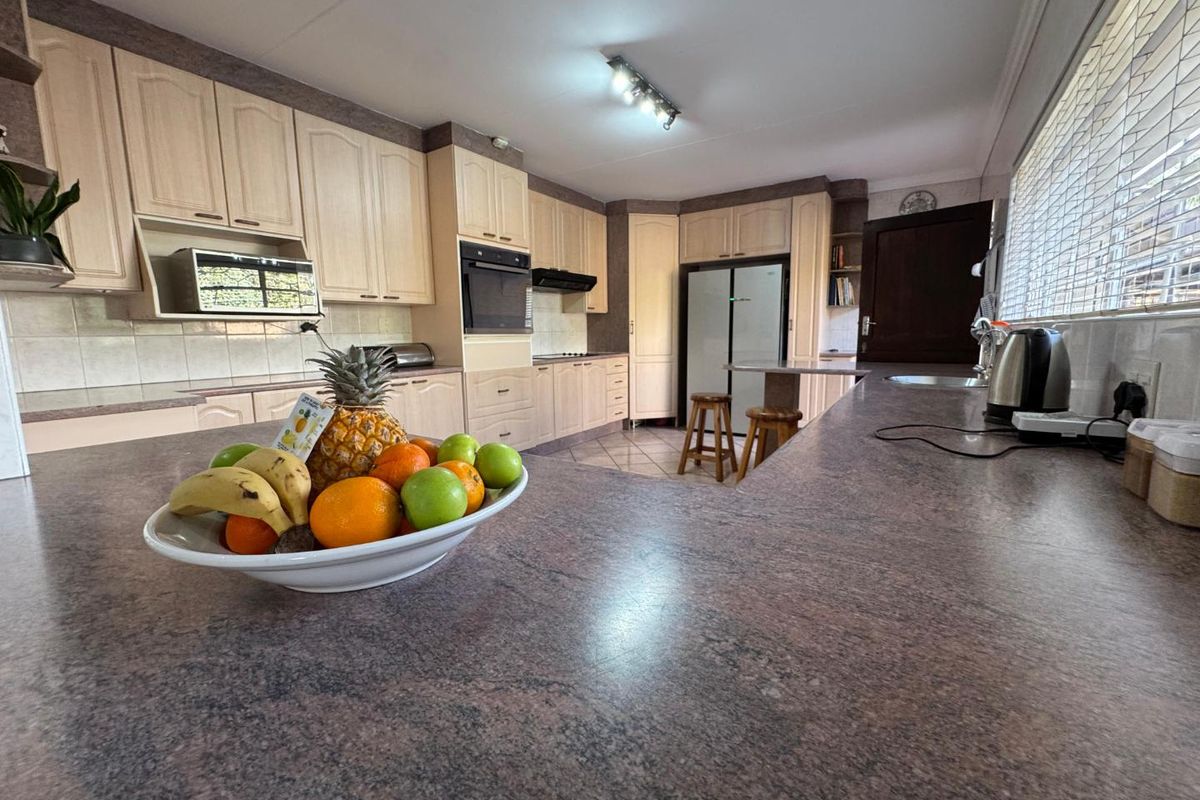 A functional kitchen featuring light wood cabinetry, granite countertops, built-in oven, and an integrated breakfast bar area with ample storage space.